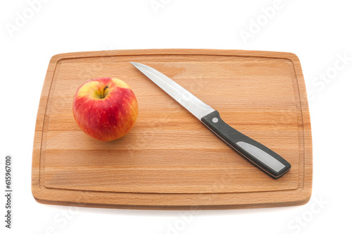 Ripe red juicy apple and knife on a cutting board made of dark wood.