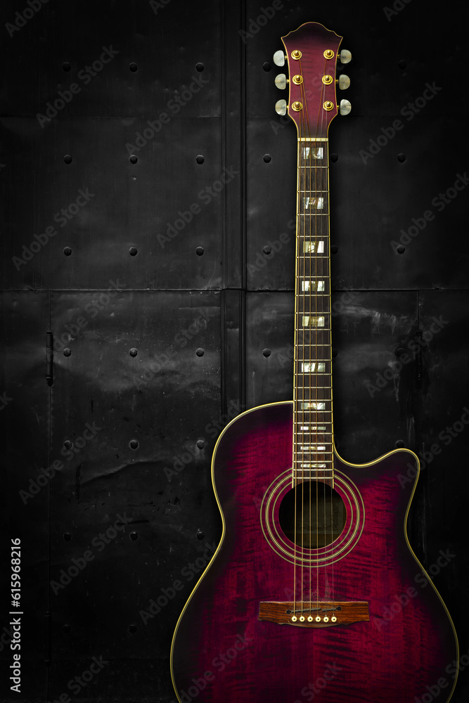 Obraz premium Photo of a purple acoustic guitar leaning up against a dark metal background.