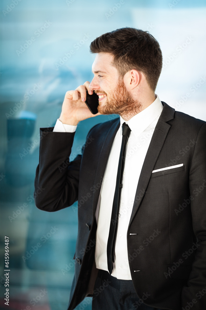 Young businessman at the office standing near window and talking on a phone Young businessman at the office standing near window and talking on a phone