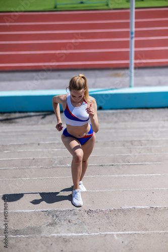 Young caucasian woman running on stadium stairs outdoors. 