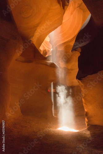 Two light beams touch ground in Upper Antelope Canyon. An angel appears in the dust illuminated from the sun beam.