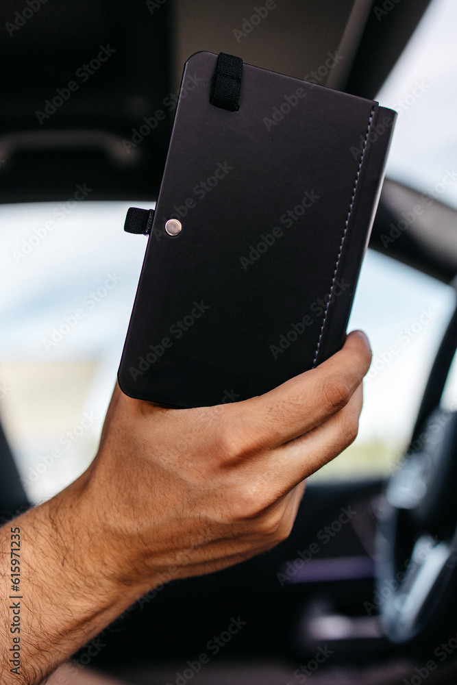 man holding a notepad and reading while sitting in an expensive car man holding a notepad and reading while sitting in an expensive car