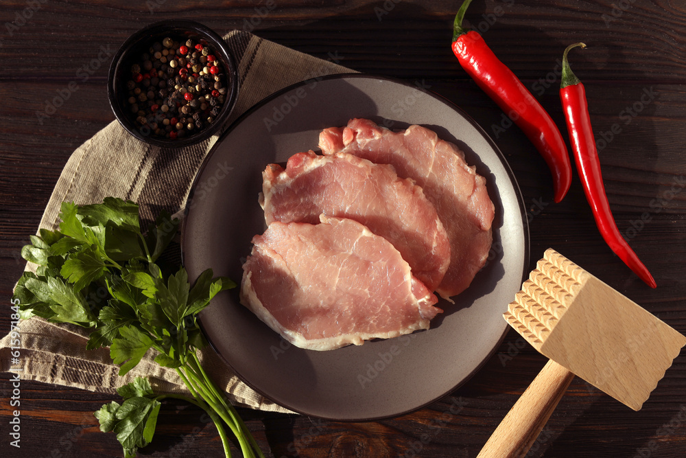 Cooking schnitzel. Raw pork slices, other ingredients and meat tenderizer on wooden table, flat lay