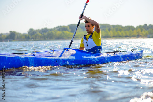 Young Professional Kayaker Paddling Kayak on the River under Bright Morning Sun. Sport and Active Lifestyle Concept