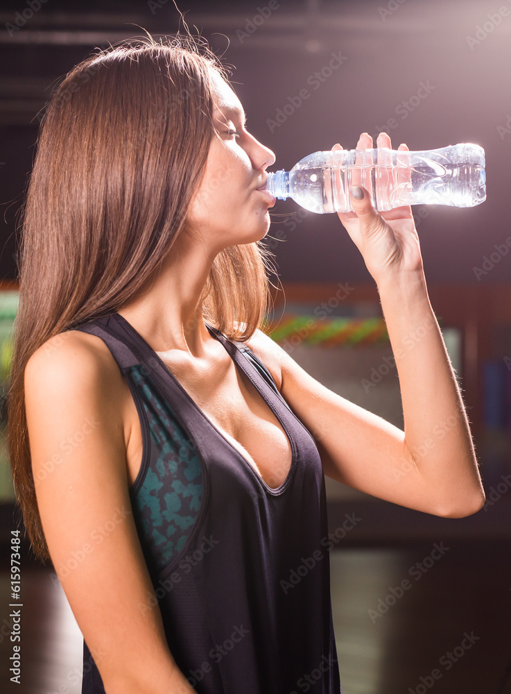 Fit young woman drinking water in the gym. Muscular woman taking break after exercise. Fit young woman drinking water in the gym. Muscular woman taking break after exercise.