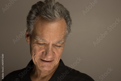 Portrait of a mature man with graying hair wearing a black shirt 60plus looking down