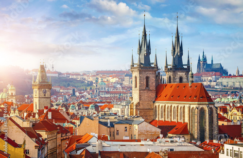 High spires towers of Tyn church in Prague city (Church of Our Lady before Tyn cathedral) urban landscape panorama with red roofs of houses in old town and blue sky with clouds