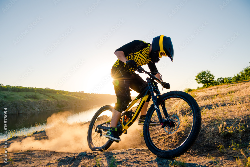 Fototapeta premium Professional Cyclist Riding the Downhill Mountain Bike on the Summer Rocky Trail at the Evening. Extreme Sport and Enduro Cycling Concept.