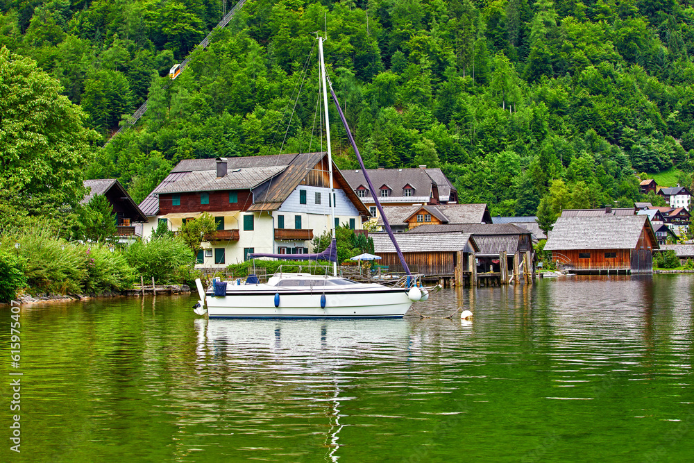 Hallstatt, Austria. View to Hallstattersee Lake and Alps mountains. Ancient houses at lake banks. Summer day. Blue sky with clouds. Hallstatt, Austria. View to Hallstattersee Lake and Alps mountains. Ancient houses at lake banks. Summer day. Blue sky with clouds.