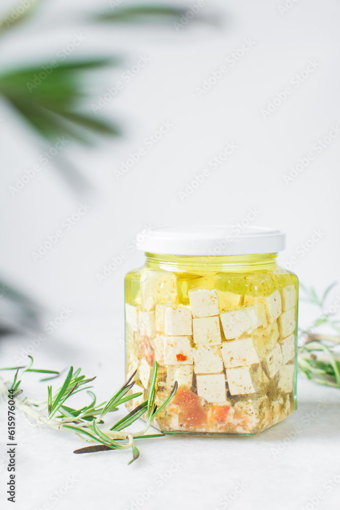 Marinated feta cheese cubes in olive oil in a glass jar. Cheese cubes