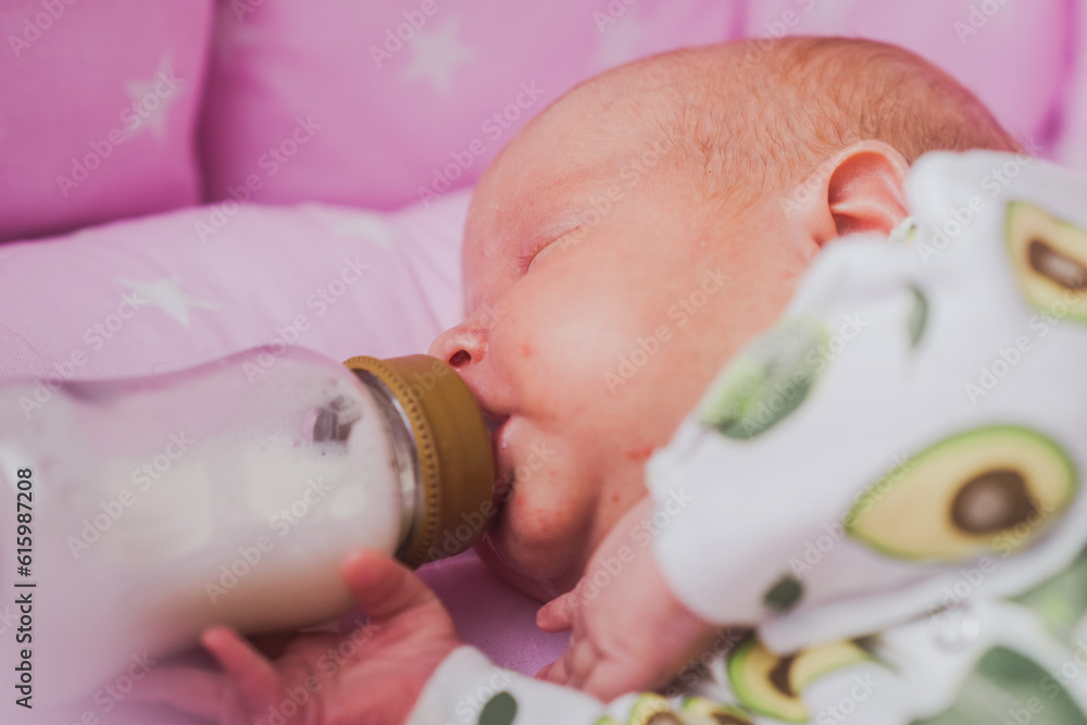A newborn baby independently drinks milk or a formula milk from a bottle, at home A newborn baby independently drinks milk or a formula milk from a bottle, at home
