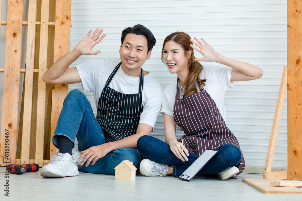 Asian professional male and female carpenter worker lover couple colleague in apron sitting on floor discussing talking writing information data short notes on clipboard in home decoration workshop Asian professional male and female carpenter worker lover couple colleague in apron sitting on floor discussing talking writing information data short notes on clipboard in home decoration workshop