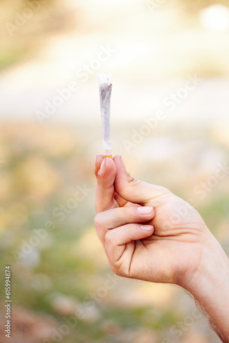Marijuana, cannabis or hand with weed joint for a calm peace to relax or help reduce pain, stress or anxiety. Trippy, smoking or closeup of person showing a blunt for mental health benefits outdoors © Jose Molina/peopleimages.com