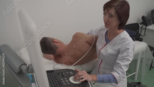 Doctor is using ultrasound machine to scan the heart of a male patient. Cardiologist makes a patient an echocardiographic test in a clinic. Patient under ultrasound examination in the hospital photo