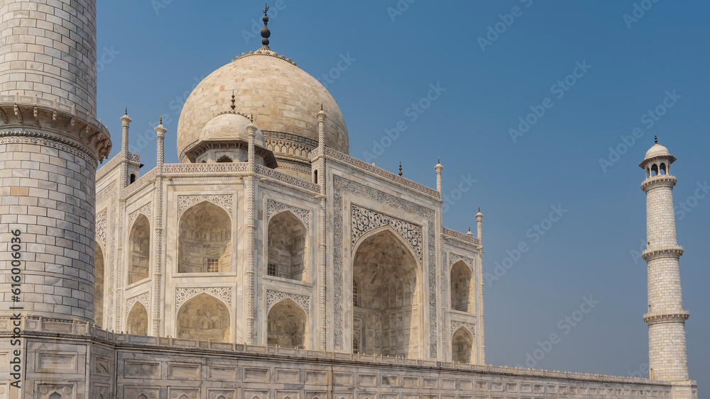 Fototapeta premium Beautiful Taj Mahal against the blue sky. Symmetrical white marble mausoleum with arches, domes, minarets. There are ornaments on the walls, inlaid with precious stones. Agra. India.