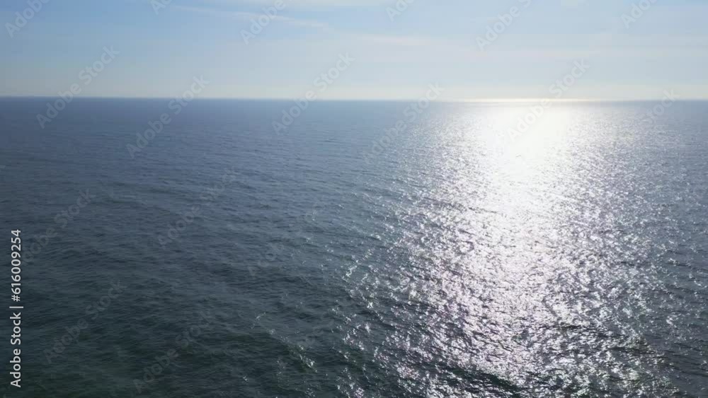 Aerial journey over the serene expanse of the calm ocean, as the golden rays of the low sun illuminate the gentle waves. Aerial journey over the serene expanse of the calm ocean, as the golden rays of the low sun illuminate the gentle waves.