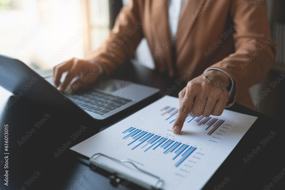 Businesswoman analyzing income charts and graphs with laptop computer. business analysis and strategy concept Business statistics, profit, financial growth rate on graph paper. financial data chart