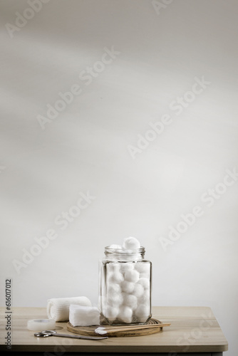 Cotton balls in a bottle on table, white room background