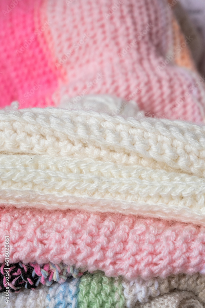 Beautiful background with knitted fabrics in soft pink and white.Knitted items stacked on top of each other. Background with knitted fabrics for advertising, banner.Vertical photo. Beautiful background with knitted fabrics in soft pink and white.Knitted items stacked on top of each other. Background with knitted fabrics for advertising, banner.Vertical photo.