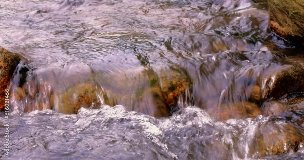 Close up on the flowing water background.The turbulent water flows through the rocky beach Close up on the flowing water background.The turbulent water flows through the rocky beach
