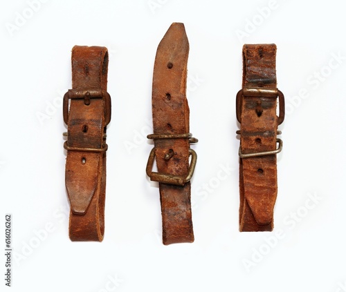 Old leather straps used to tie up skis togetner. Natural leather belts on white, flat lay. photo