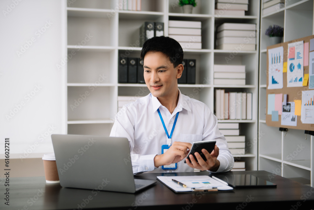 Confident Asian man with a smile standing holding notepad and tablet at the modern office. Confident Asian man with a smile standing holding notepad and tablet at the modern office.