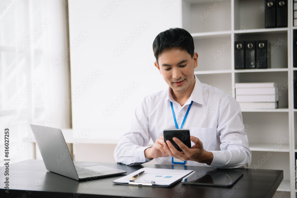 Confident Asian man with a smile standing holding notepad and tablet at the modern office. Confident Asian man with a smile standing holding notepad and tablet at the modern office.