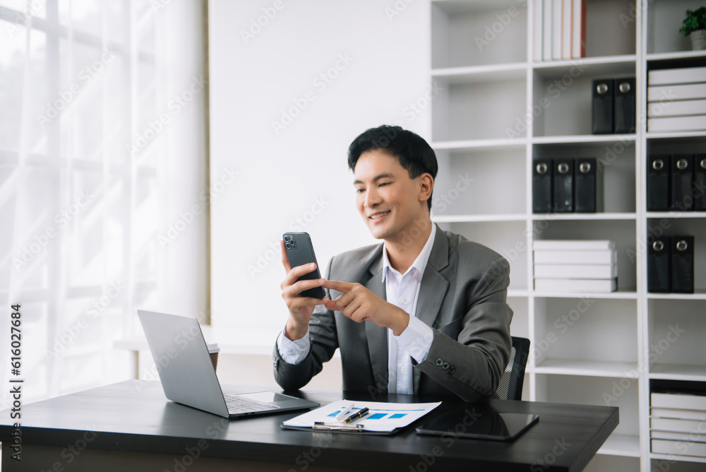 Young Asian business man using laptop and tablet while sitting at her working place. Concentrated at work. Young Asian business man using laptop and tablet while sitting at her working place. Concentrated at work.