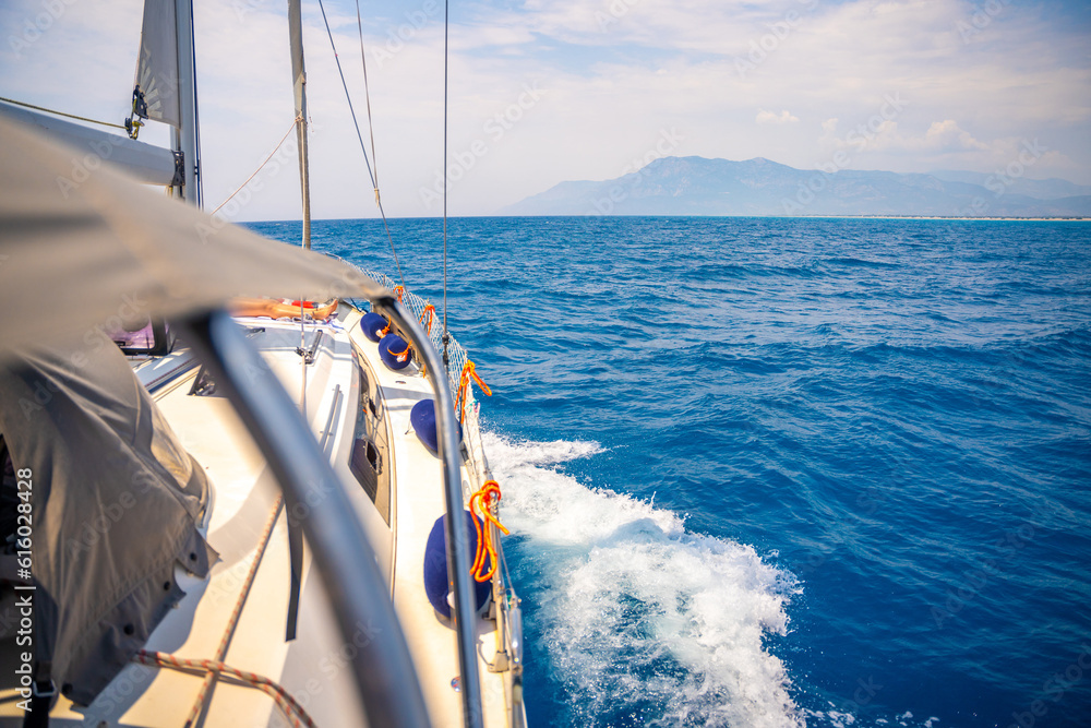 Obraz premium Yacht sailing in an open sea. Close-up view of side of the boat. Clear sky after the rain, waves and water splashes