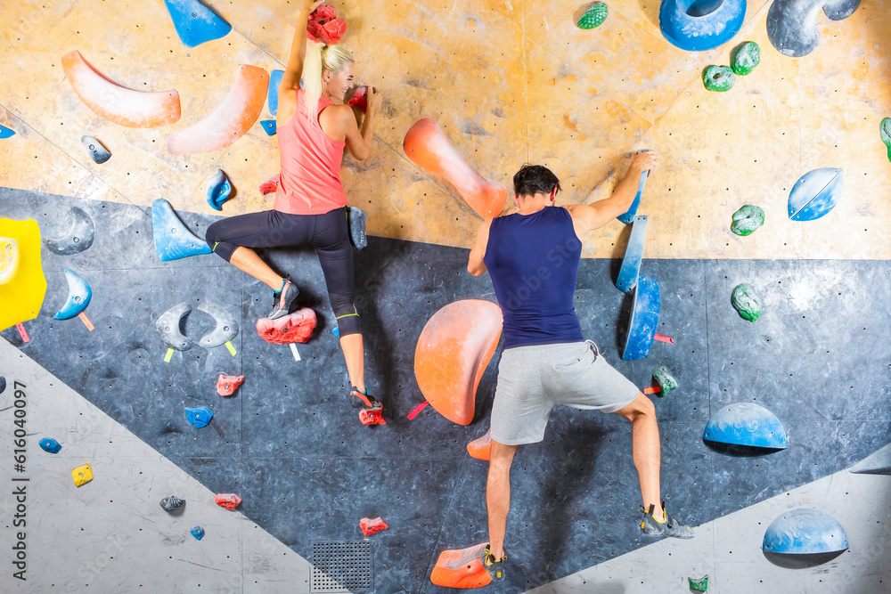 Obraz premium Sporty Couple of Caucasian Athletes Climbing Up Together on Steep Rock climbing on artificial wall indoors As Extreme sports and bouldering concept.