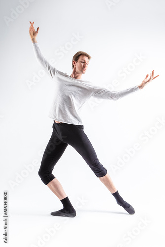 One Caucasian Handsome Young Man Dancing Ballet Posing with Lifted hands in White Shirt On White