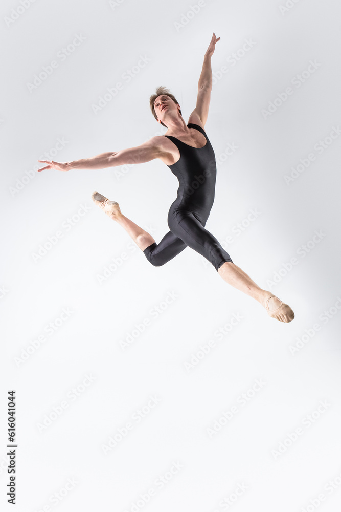 Professional Ballet Dancer Young Caucasian Athletic Man in Black Suit Dancing in Studio Over White Background With Lifted Hands.