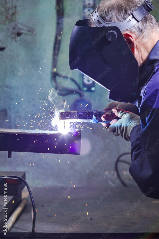 Welding Process With Sparks of Professional Welder in Protective Mask During Welding Process of Metal Construction At Factory. Welding Process With Sparks of Professional Welder in Protective Mask During Welding Process of Metal Construction At Factory.