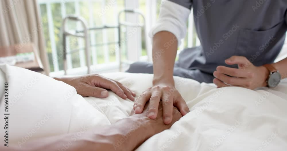 Mid section of diverse male doctor discussing with senior male patient in bed at home, slow motion Mid section of diverse male doctor discussing with senior male patient in bed at home, slow motion