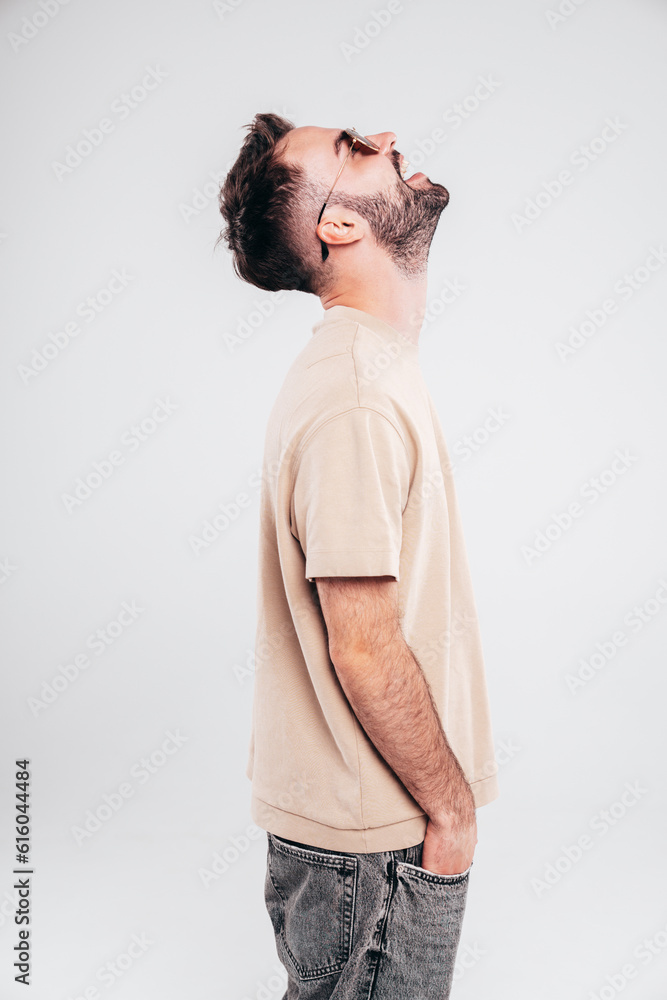 Portrait of handsome smiling stylish hipster lambersexual model. Sexy man dressed in T-shirt and jeans. Fashion male isolated on white background in studio. In sunglasses Portrait of handsome smiling stylish hipster lambersexual model. Sexy man dressed in T-shirt and jeans. Fashion male isolated on white background in studio. In sunglasses