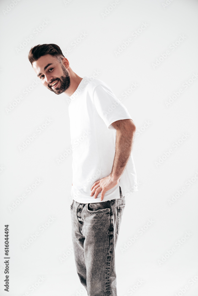 Portrait of handsome smiling stylish hipster lambersexual model. Sexy man dressed in white T-shirt and jeans. Fashion male isolated on white background in studio Portrait of handsome smiling stylish hipster lambersexual model. Sexy man dressed in white T-shirt and jeans. Fashion male isolated on white background in studio