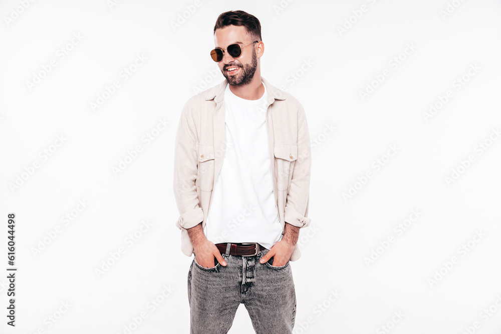 Portrait of handsome smiling stylish hipster lambersexual model. Sexy man dressed in white T-shirt and jeans. Fashion male isolated on white background in studio. In sunglasses Portrait of handsome smiling stylish hipster lambersexual model. Sexy man dressed in white T-shirt and jeans. Fashion male isolated on white background in studio. In sunglasses