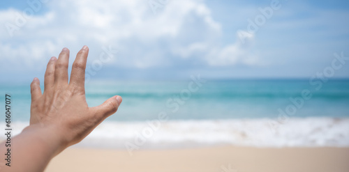 Woman hand reach out to summer tropical beach with blue sky background.