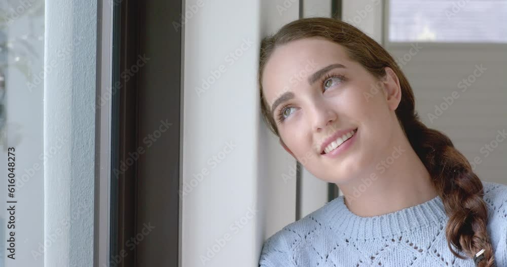 Thoughtful caucasian woman touching her face and smiling at window in slow motion Thoughtful caucasian woman touching her face and smiling at window in slow motion
