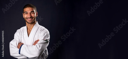 a smiling young men wearing karate clothes in dark blue navy background generative ai