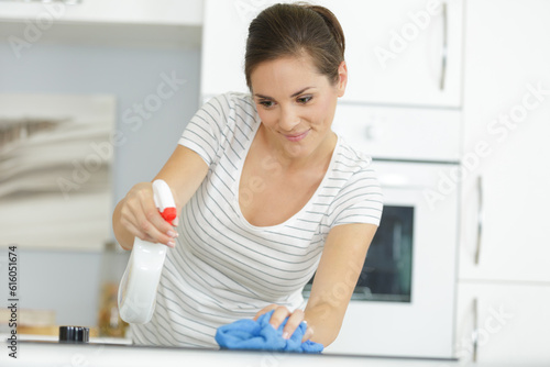 Fototapeta Naklejka Na Ścianę i Meble -  woman spraying kitchen table and cleaning it