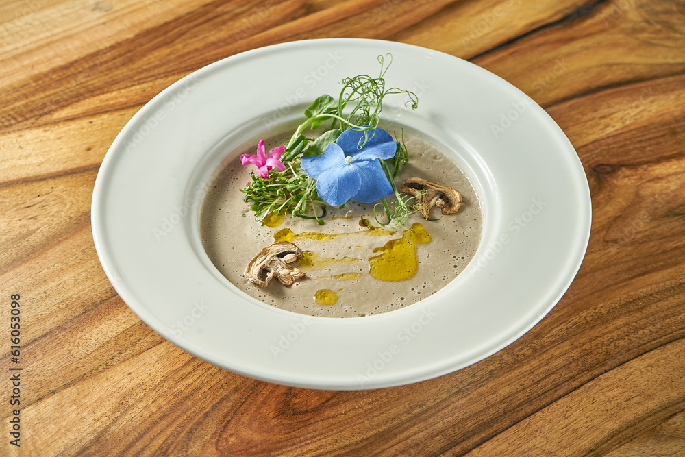 Cream of mushroom soup with decorative flowers in a white plate. Vegetarian food Cream of mushroom soup with decorative flowers in a white plate. Vegetarian food