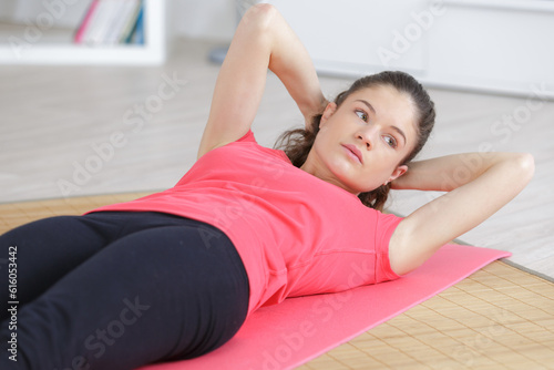 young woman exercising at home on a mat