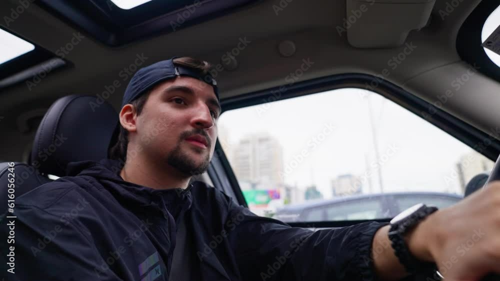 Young boy driving sitting in a car. Looking around and paying attention to the traffic. Bearded surfer driver traveling. Slow motion video.. Young boy driving sitting in a car. Looking around and paying attention to the traffic. Bearded surfer driver traveling. Slow motion video..