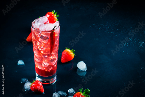 Red alcoholic cocktail drink with vodka, grapefruit juice, strawberries, sugar and hot chili pepper. Highball glass on dark blue background photo