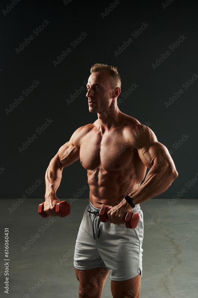 caucasian athlete pulls dumbbells with arm strength pumping chest muscles. a man goes in for sports and keeps himself in great shape of the body caucasian athlete pulls dumbbells with arm strength pumping chest muscles. a man goes in for sports and keeps himself in great shape of the body