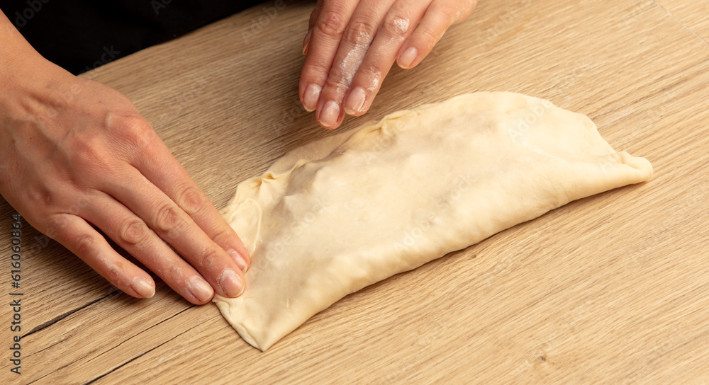 Female hands kneading dough on a wooden table. Close-up