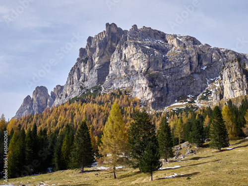 In an alpine setting, the majestic Dolomites are tinged with the warm autumn colors, while the imposing larches are colored with orange and gold, creating a breathtaking spectacle
