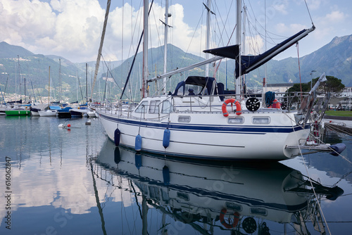A beautiful white sailing ship is elegantly moored in the placid waters of a picturesque Italian lake port.