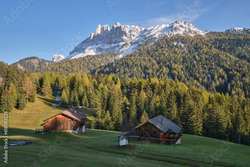 In an alpine setting, the majestic Dolomites are tinged with the warm autumn colors, while the imposing larches are colored with orange and gold, creating a breathtaking spectacle photo